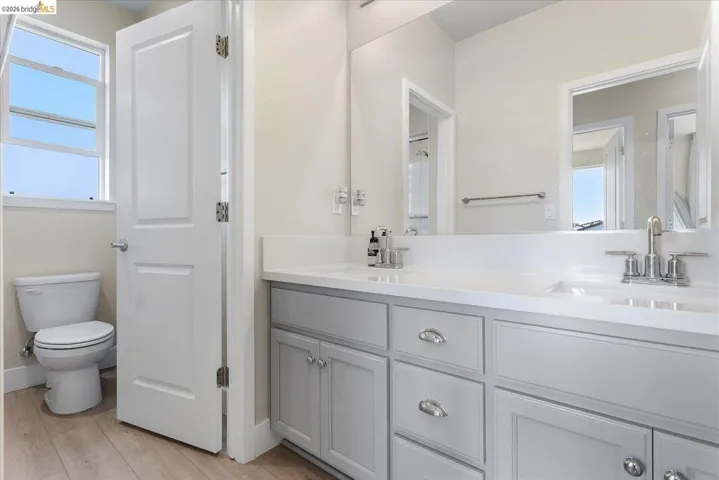 Dual vanity with integrated sinks, light gray cabinetry, and polished chrome fixtures