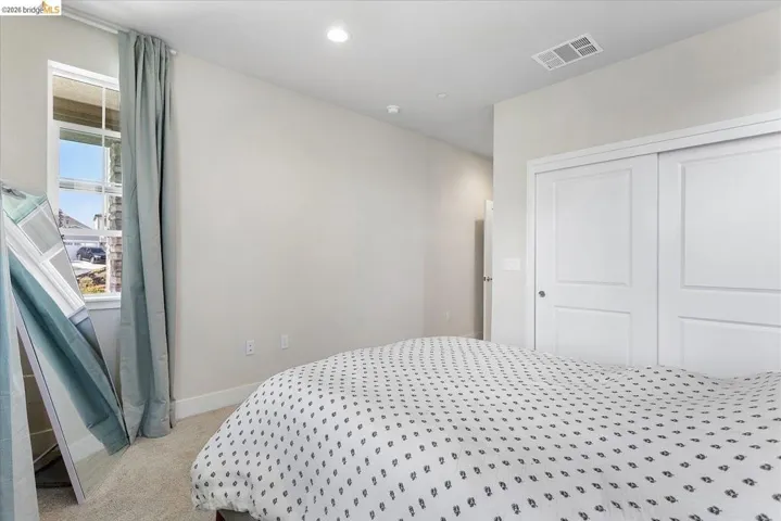 Bedroom featuring neutral wall paint, recessed lighting, carpet flooring, a window with vertical blinds, and a built-in closet with sliding panel doors