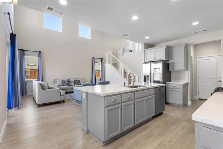 Open-concept living space with a kitchen island featuring a sink and dishwasher