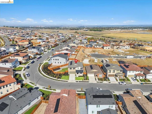Aerial view of a residential community featuring a cul-de-sac street design, varied rooflines, solar panel installations, and new construction development