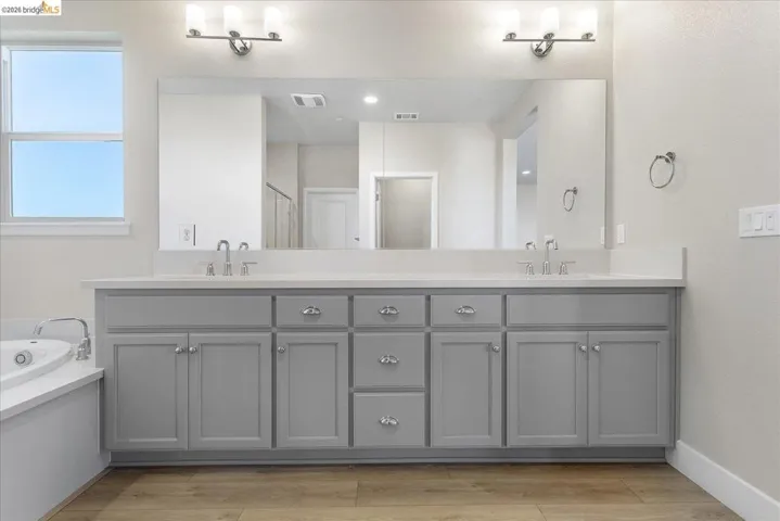 Dual vanity featuring light gray cabinetry, chrome hardware, undermount sinks, and a large integrated mirror