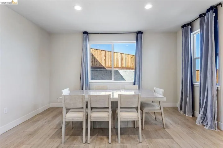Dining space featuring wood-finish flooring, two large windows, white baseboards, and recessed lighting