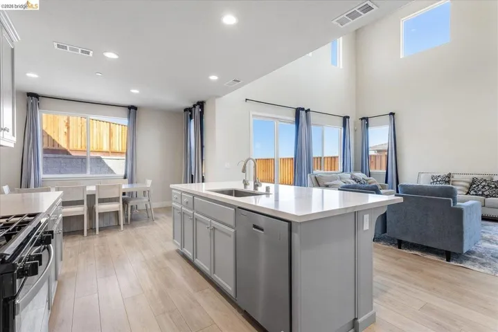 Open-concept living area with a kitchen island featuring a stainless steel sink, a gas range, and wood-finish flooring throughout