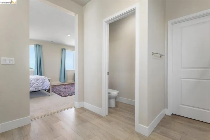 Hallway featuring wood-finish flooring, white baseboards, and neutral wall tones
