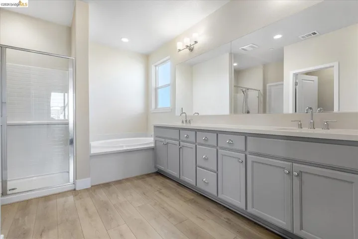 Spacious bathroom featuring a dual vanity with light gray cabinetry and a large mirror