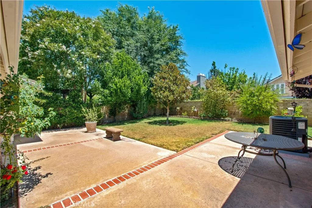 Back yard from corner of home, including concrete patio with brick inlays.
