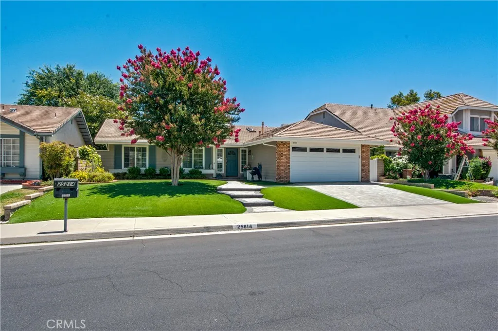 Front of home including artificial grass and crape myrtle tree in bloom.