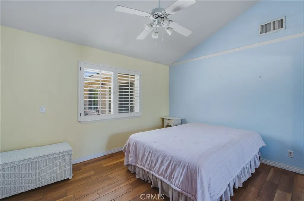 2nd bedroom next to primary bedroom including vaulted ceiling and fan with light.