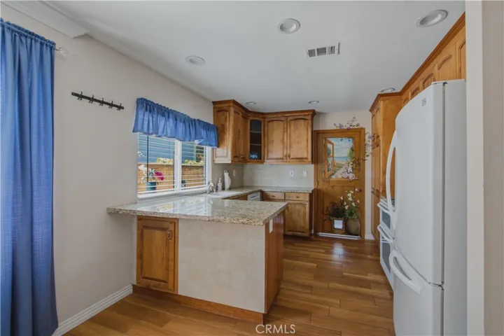 View of kitchen from dining room area including all white appliances and custom painted door into garage.