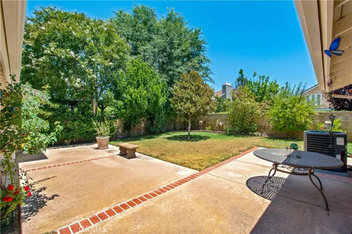 Back yard from corner of home, including concrete patio with brick inlays.