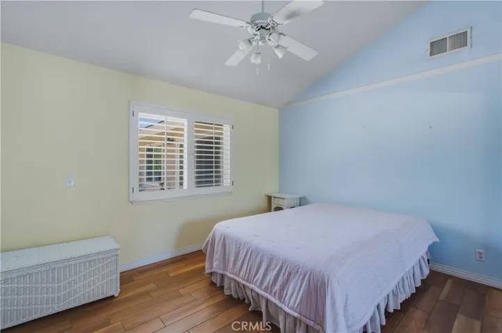2nd bedroom next to primary bedroom including vaulted ceiling and fan with light.