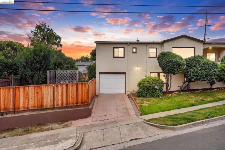 Sloped property with a stucco exterior, integrated garage, and a concrete driveway