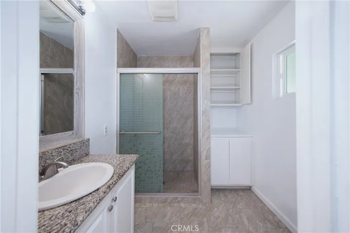 The primary ensuite has a granite countertop, a floor to ceiling tiled shower and cabinetry for extra storage.
