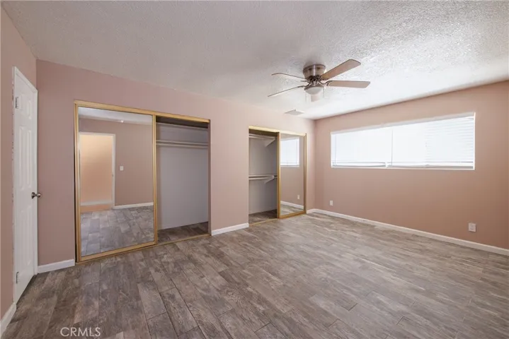 The spacious primary bedroom is at the end of the hallway and has a ceiling fan, a large window and two large closets