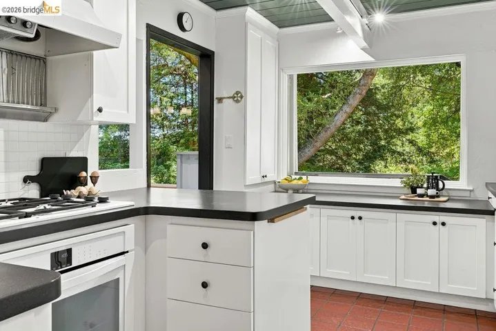 Kitchen featuring white cabinetry with black hardware, dark countertops, a built-in oven, and a gas range