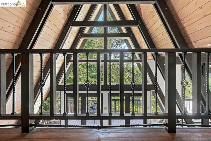 Interior balcony featuring wood-finish flooring and black metal balusters with decorative twisted elements