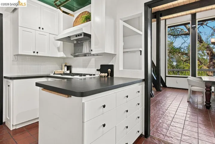 Contemporary kitchen featuring white cabinetry with black hardware, dark countertops, and a white subway tile backsplash