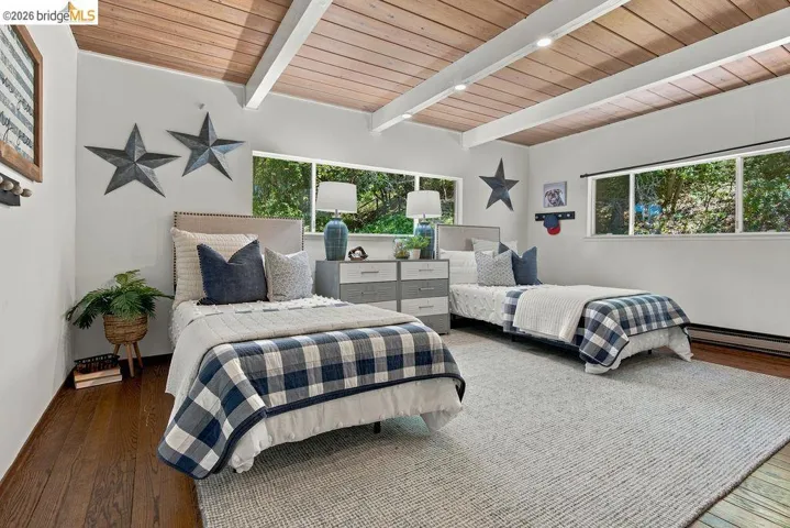 Exposed beam ceiling with wood-finish panels, multiple windows, and wood-finish flooring