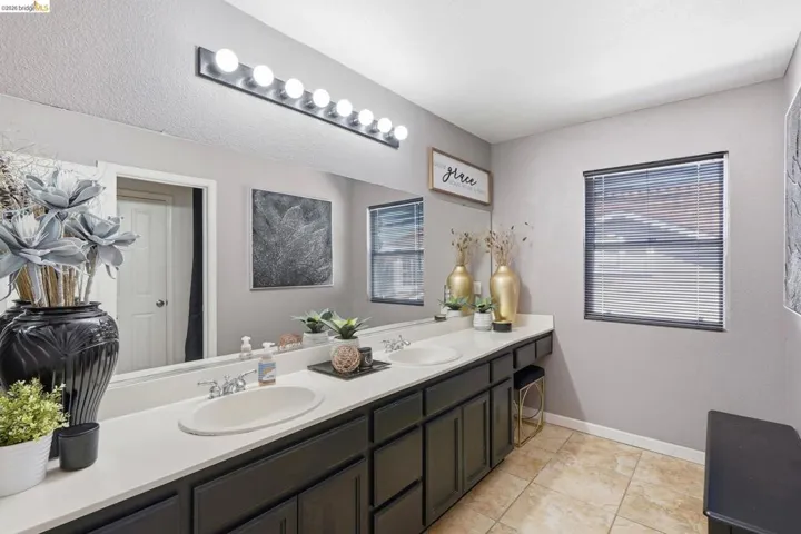Bathroom with a dual vanity featuring dark cabinetry and light-toned countertops