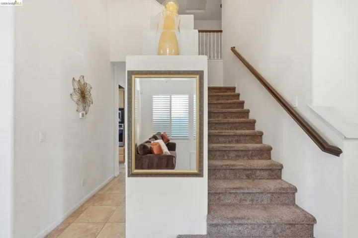 Staircase featuring textured carpeting and a wooden handrail