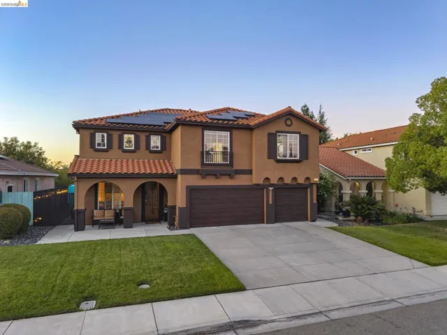 Spanish-style facade featuring a tile roof, solar panels, and a prominent arched entry