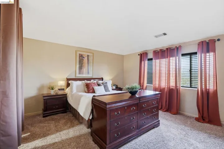 Carpeted room with neutral wall tones and multiple windows