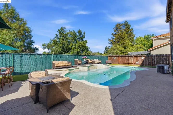 Freeform swimming pool with integrated spa and surrounding concrete patio