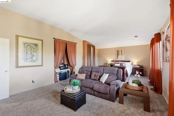 Spacious interior room featuring vaulted ceilings, neutral wall tones, and plush carpeting throughout