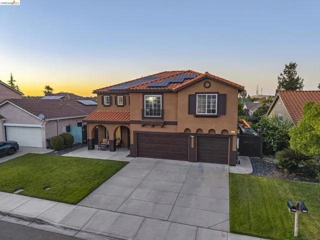 Mediterranean-style residence featuring a tile roof, solar panels, and a prominent arched entry