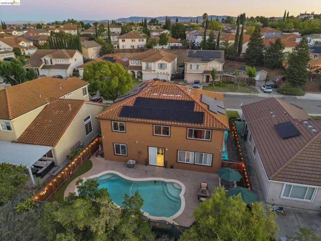 Two-story stucco exterior residence with a tile roof and integrated solar panels