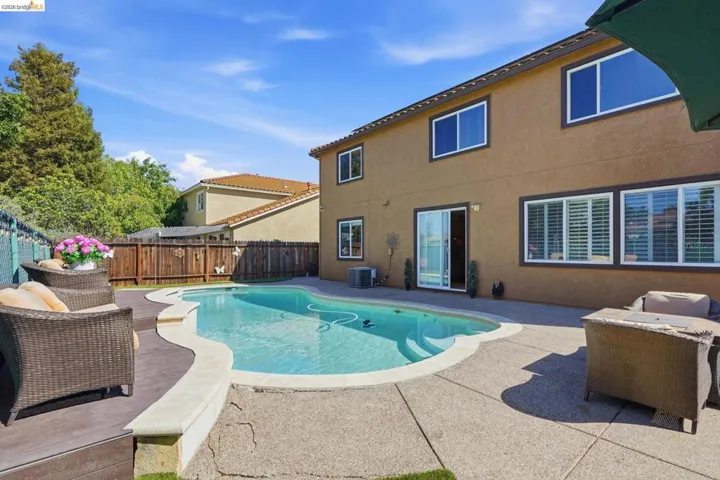 Backyard featuring a freeform swimming pool with concrete decking, a wood-finish deck platform, and a sliding glass door entry to the home