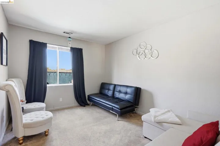 Carpeted interior space with neutral wall tones and a window featuring dark drapery