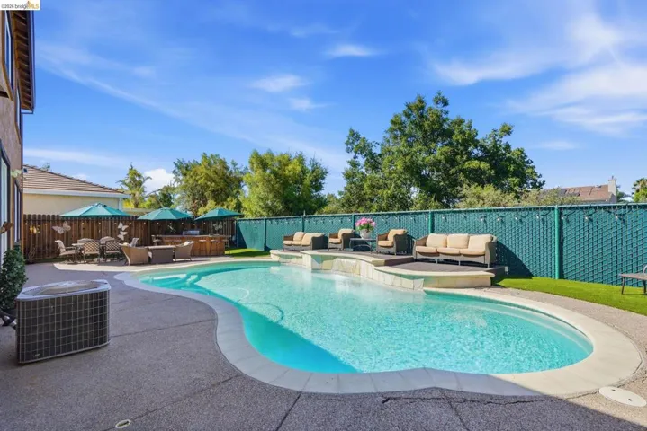 Curved swimming pool with light blue interior and concrete coping