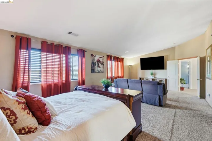 Carpeted interior space featuring multiple windows with blinds and curtains