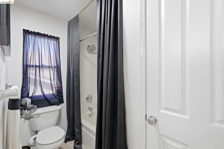 Bathroom featuring a window, white paneled door, and a shower-over-tub combination with chrome fixtures