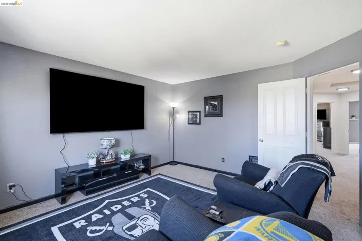 Carpeted room featuring light gray walls, a white ceiling, and a white interior door with a paneled design
