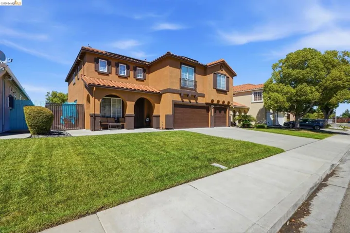 Stucco exterior with a tile roof, an arched entry, two garage doors, and a manicured front lawn