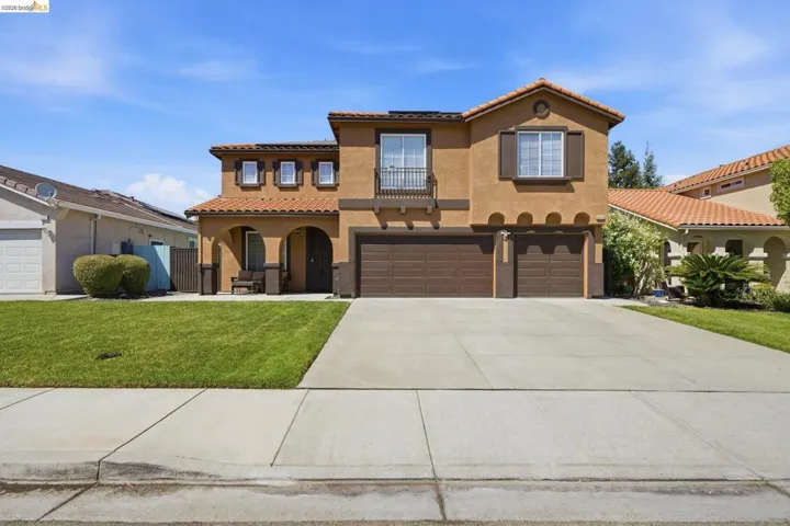 Stucco exterior with a tile roof, featuring a two-car garage, an arched entry porch, and a second-story balcony