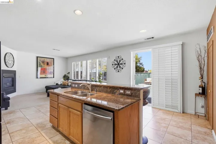 Kitchen island with dual stainless steel sinks, granite countertops, and integrated dishwasher