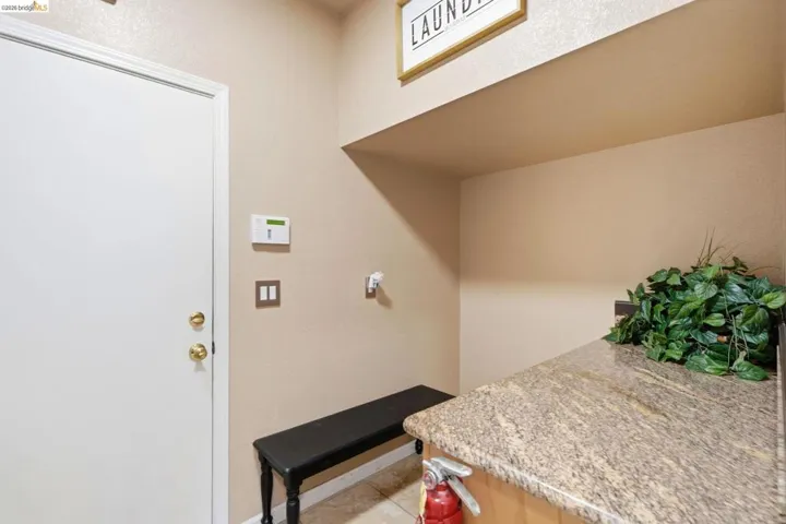 Utility area featuring a granite-look countertop, light wood-finish cabinetry, and a white interior door with brass hardware