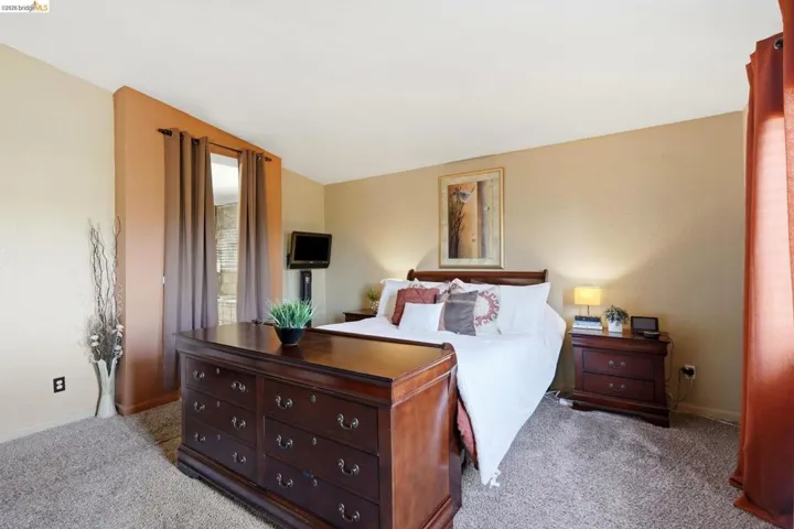 Carpeted room with a partial wall partition, dual-toned wall paint, and a window with privacy drapes
