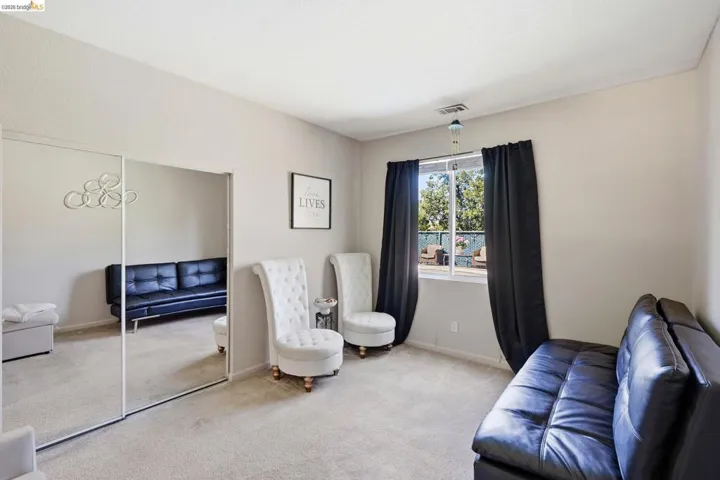 Carpeted room featuring a large window with dark drapes, mirrored closet doors, and recessed lighting