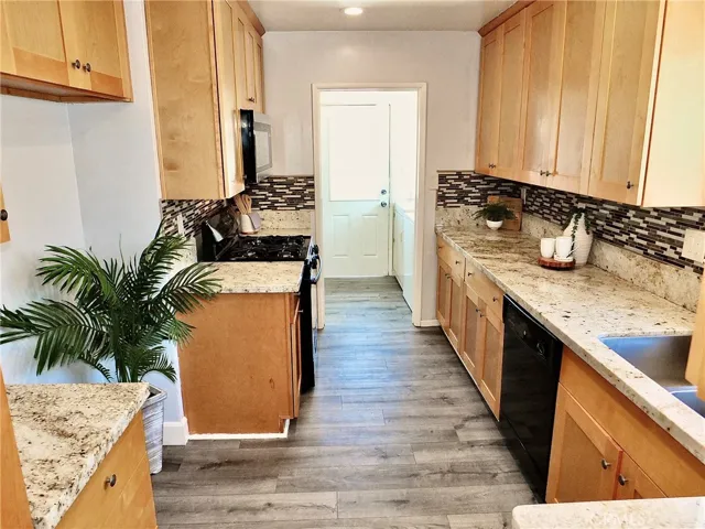 Remodeled kitchen featuring self closing cabinetry and drawers, granite countertops, stainless steel sink, gas range, and a new built- in microwave.