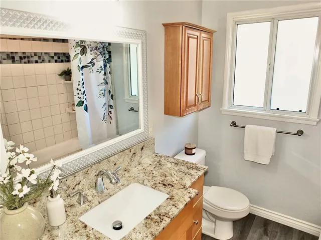 remodeled bathroom vanity with cabinet above toilet and tiled tub/shower combination