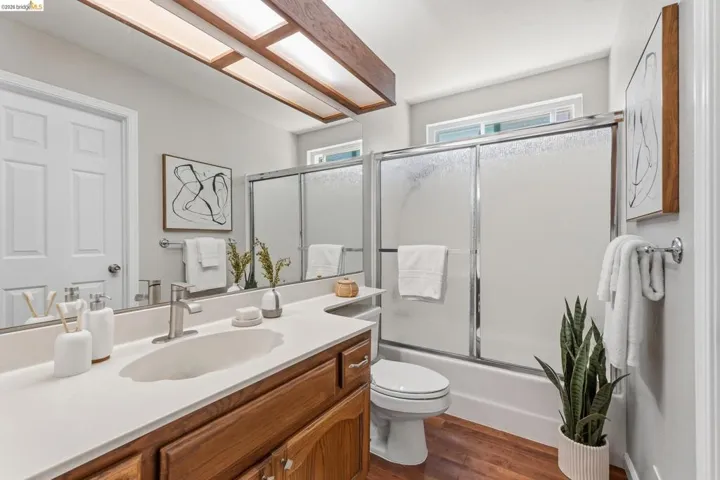 Bathroom featuring a wood-finish floor, light gray walls, and a white countertop vanity with a wood-finish base