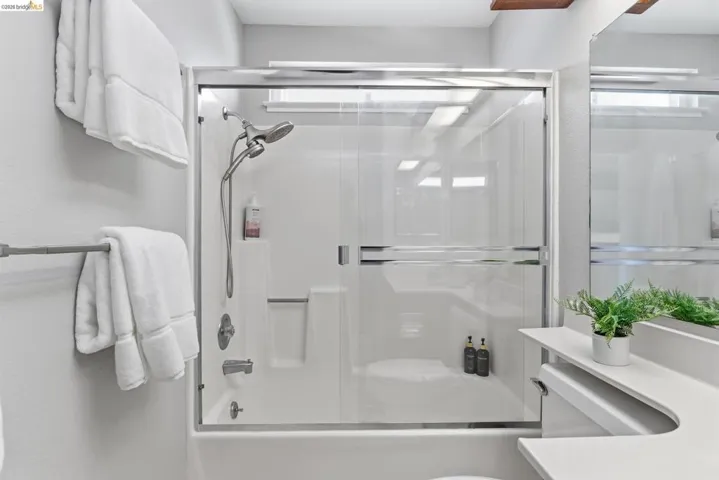 Shower and tub combination with glass sliding door enclosure and built-in shelving