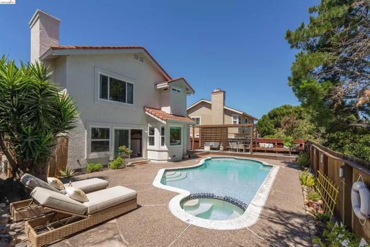 Rear exterior with a free-form pool, integrated spa, and expansive concrete patio