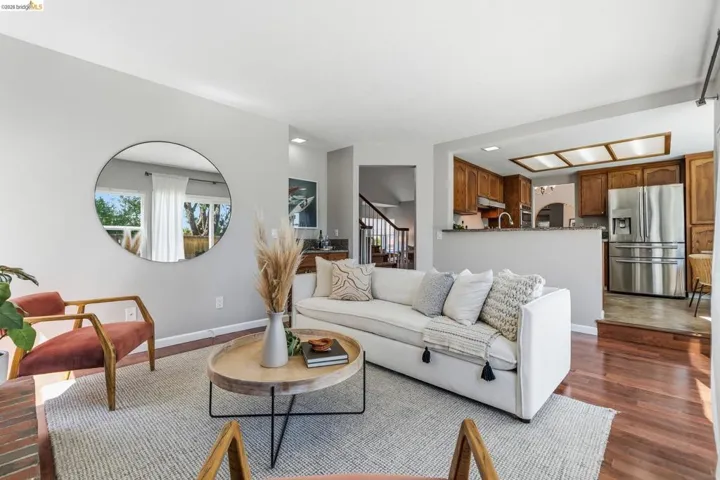 Living area featuring wood-finish flooring, light grey walls, and a circular wall mirror