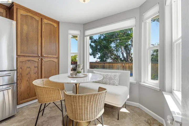 Light-filled kitchen nook featuring expansive windows, wood-finish cabinetry, a built-in banquette, and tile flooring