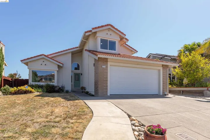 Exterior featuring stucco siding with stone accents, a tile roof, an attached two-car garage, an arched entryway, and a prominent bay window